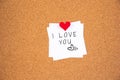 I love you lettering on white paper pinned with big felt heart pushpin on cork board Royalty Free Stock Photo