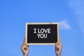 I LOVE YOU / Man holding small blackboard on blue sky background Royalty Free Stock Photo