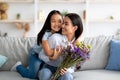 I love you, mommy. Excited asian girl greeting mom with birthday or mother& x27;s day, giving her flowers and embracing Royalty Free Stock Photo