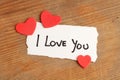 I love You phrase write on a piece of paper with three red hearts on a wooden table Royalty Free Stock Photo