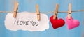 I LOVE YOU word on paper and couple heart shape decoration hanging on line with copy space for text on blue wooden background. Royalty Free Stock Photo