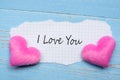 I LOVE YOU word on paper note with couple pink heart shape decoration on blue wooden table background. Wedding, Romantic and Happy Royalty Free Stock Photo