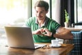 I love you. Young happy romantic businessman in green t-shirt sitting and looking ot laptop screen on video call with love gesture Royalty Free Stock Photo