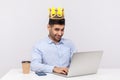 I`m boss! Positive ambitious top manager, office employee with crown on head working on laptop and smiling