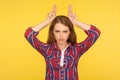 I`m a cow. Portrait of angry menacing ginger girl in checkered shirt showing bull horns on head, threatening to attack Royalty Free Stock Photo