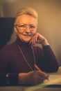 Senior woman signing document at home. Looking at camera Royalty Free Stock Photo