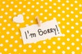i\'m sorry phrase write on a white paper on a yellow with white polka dots background