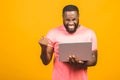 I`m winner! Excited happy afro american man looking at laptop computer screen and celebrating the win isolated over yellow Royalty Free Stock Photo