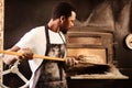 I make them fresh every day. a male baker removing freshly baked bread from the oven.