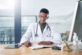 I might have an early day after a few cancellations. a handsome young doctor sitting alone in his office at the clinic Royalty Free Stock Photo