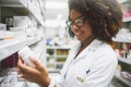 I might need some of this at home. a cheerful young female pharmacist reading the label of a medication bottle inside of Royalty Free Stock Photo