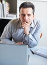 I need a break...Portrait of an exhausted-looking businessman sitting in front of his laptop at his desk.