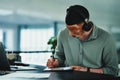 I need music to get me going. a young businessman doing paperwork while wearing headphones in an office at work. Royalty Free Stock Photo