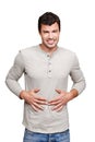 I need something to stop the pain. A young man rubbing his stomach and grimacing while isolated on a white background.