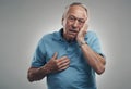 I need to lie down this is too much stress. an old man touching his hand to his face in a studio against a grey Royalty Free Stock Photo