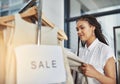 I never knew I needed this - until now. a woman looking at dresses on a rail with a sign that reads sale. Royalty Free Stock Photo