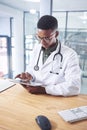 I never miss a detail on reports. a handsome young doctor sitting alone in his office at the clinic and using his Royalty Free Stock Photo