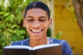 I never start my days without reading my bible. a handsome young man sitting alone outside and reading a book during the Royalty Free Stock Photo