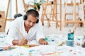 I paint better when I listen to music. a handsome young artist sitting alone and painting while listening to music Royalty Free Stock Photo