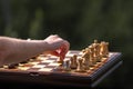 I am playing chess alone. Female hand moves pawn on chessboard with set pieces. Wooden Chessboard and Chess Pieces