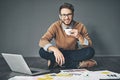 I prefer working in a more casual environment. Studio portrait of a young businessman working on a laptop against a grey Royalty Free Stock Photo