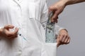 I put money in the woman doctorâs pocket, several hundred dollar bills, and a white doctorâs coat. Royalty Free Stock Photo