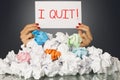 I quit, decision of exhausted employee on white paper, behind a stack of wastepaper