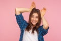 I am rabbit! Portrait of amazing playful pretty girl in checkered shirt showing bunny ears gesture, laughing