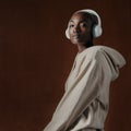 I rock to my own beat. Studio portrait of an attractive young woman wearing headphones and posing against a brown Royalty Free Stock Photo