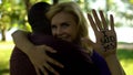 I said yes phrase written on palm, joyful lady hugging african american groom