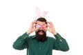 I see spring is coming. Bearded man hold eggs as glasses. Hipster wear bunny ears. Rabbit bringing eggs in spring