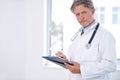 I see your last checkup was five years ago. Portrait of a mature doctor standing in his office and holding a clipboard. Royalty Free Stock Photo