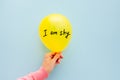 I am shy - woman hand is holding air balloon with text on light blue background, introvert type and psychology