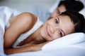 I slept so well...Smiling young woman lying in bed alongside her boyfriend.