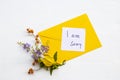 I am sorry message card handwriting with yellow envelope, yellow flower ylang ylang and little purple