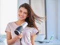 I spend a lot of time taking care of my hair. Cropped portrait of a beautiful young woman blowdrying her hair in the