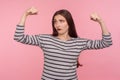 I am strong! Portrait of confident independent woman in striped sweatshirt raising hands showing biceps