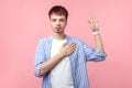 I swear! Portrait of honest serious brown-haired man keeping hand on chest and making promise oath. isolated on pink background Royalty Free Stock Photo