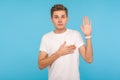 I swear! Portrait of honest sincere man in t-shirt giving promise with hand on heart, pledging allegiance