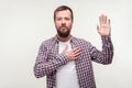 I swear! Portrait of responsible bearded man keeping hand on chest making promise. isolated on white background