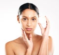 I swear by it. Studio portrait of an attractive young woman applying lotion against a grey background.