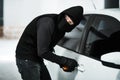 I think I heard someone coming. a masked criminal picking the lock of a car door inside a parking lot. Royalty Free Stock Photo