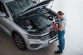 I think I done with this automobile. Man in blue uniform works with broken car. Making repairings Royalty Free Stock Photo