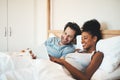 I think we should go here for our second honeymoon. an affectionate young couple using a digital tablet together in bed