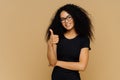 I totally agree. Good looking satisfied Afro American woman keeps thumb up, dressed in casual black t shirt, has crisp hair, wears