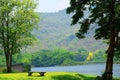 Grass yard with a seat on bank of the local river on mountain background 1