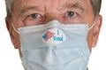 I Voted paper sticker on mans face mask against white background