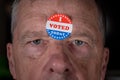 I Voted Today paper sticker on mans forehead with angry stare at camera