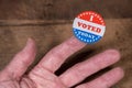 I Voted Today paper sticker on mans finger on rustic wooden table