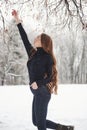 I wanna to reach that branch. Pretty girl with long hair and in black blouse is in the winter forest